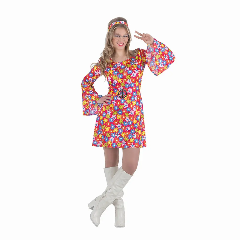 Mujer de frente posando con una mano en la cadera haciendo el gesto de victoria, luciendo el disfraz de hippie mujer años 70 de flores de la tienda Disfraces Lucero compuesto por un vestido corto de flores multicolor con mangas de campana, cinta del pelo, gafas, collar de la paz y botas blancas.