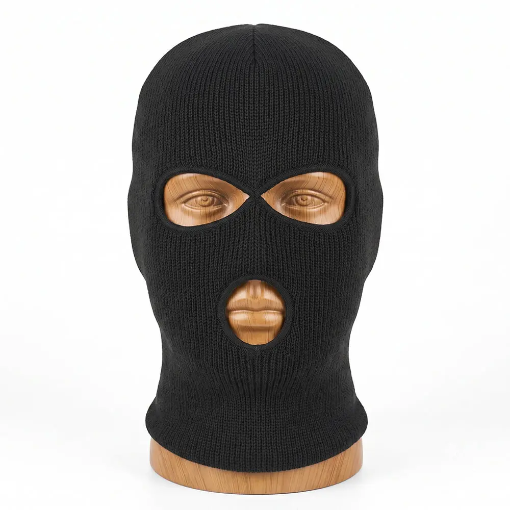 Pasamontaña negro de punto de tres agujeros (dos ojos y boca) colocado sobre un busto de madera, que muestra en detalle su textura de lana tejida fina y sus orificios con costuras reforzadas de la tienda Disfraces Lucero.